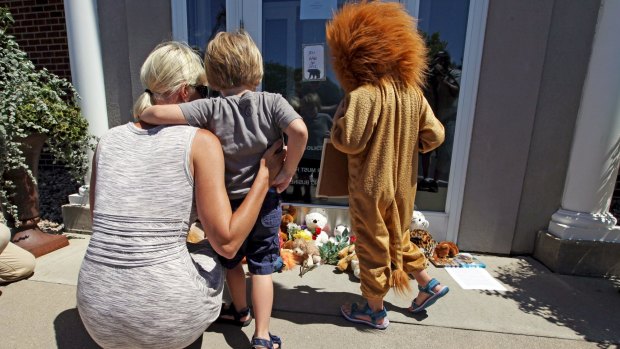 Sarah Madison (left) with her son Beckett, 3, and daughter Quinn, 5 (in costume) outside Dr Walter Palmer's River Bluff Dental clinic where a stuffed animal collection is growing in protest over Cecil's killing.