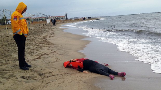A Turkish rescue worker looks at the body of a migrant lying on the beach in Ayvalik.