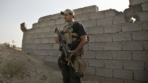 Smoke rises in the distance as a soldier with Iraq's elite counterterrorism forces stands guard at the edge of the Shuhada neighbourhood in Islamic State-held Fallujah on Wednesday. 