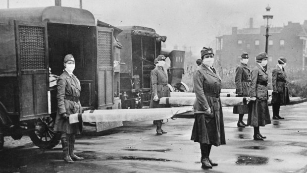 In this October 1918 photo, St Louis Red Cross Motor Corps personnel wear masks as they hold stretchers next to ambulances in preparation for victims of the Spanish flu epidemic. 
