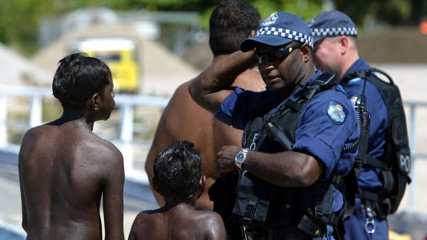 Young local aboriginal kids play on the main wharf on Palm Island with Police officers from the Personal Safety Response Team in the wake of the Palm Island riots.