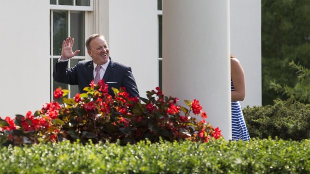 Outgoing White House press secretary Sean Spicer, left, waves while walking to the West Wing of the White House.