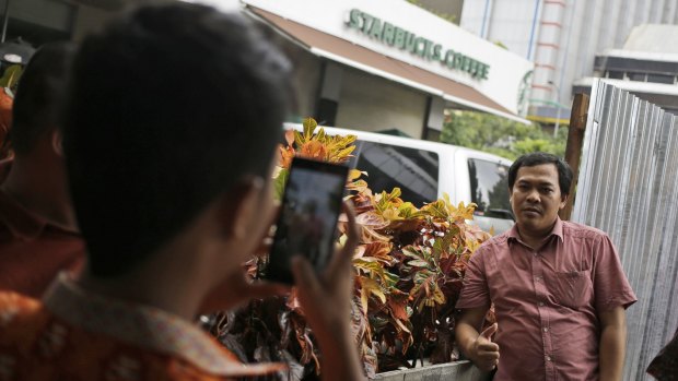 A man poses for a photo on Friday outside the Starbucks cafe where Thursday's attack occurred in Jakarta.