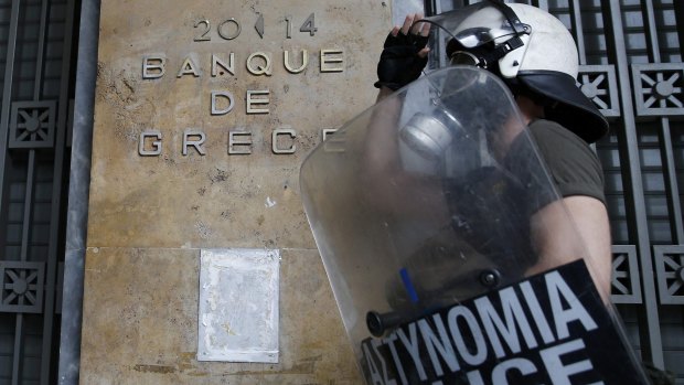 A riot police officer adjusts his helmet in front of the Bank of Greece in Athens.