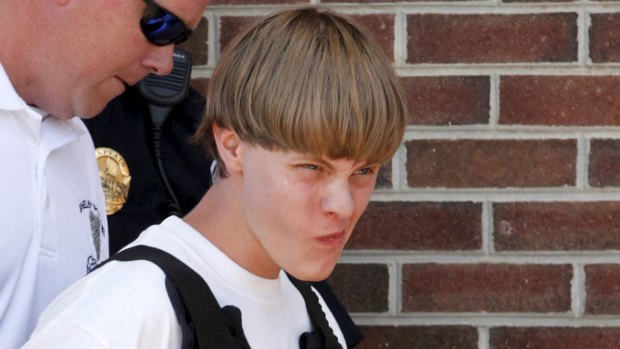 Police lead suspected shooter Dylann Roof, 21, into the courthouse in Shelby, North Carolina, where he has been charged with nine counts of murder and possession of a firearm.