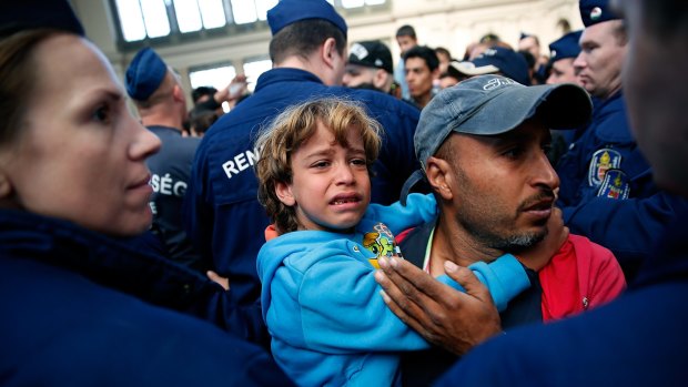 A boy cries as his father attempts to convince Hungarian police to allow his  family to cross a police line at Keleti train station in Budapest.