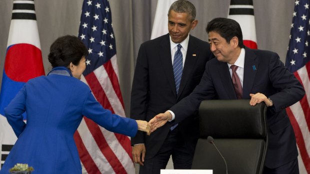 South Korean President Park Geun-hye, left, shakes hands with Japanese Prime Minister Shinzo Abe as President Barack Obama watches on Thursday. Donald Trump has said the two Asian countries should step up nuclear weapon plans because of North Korea.