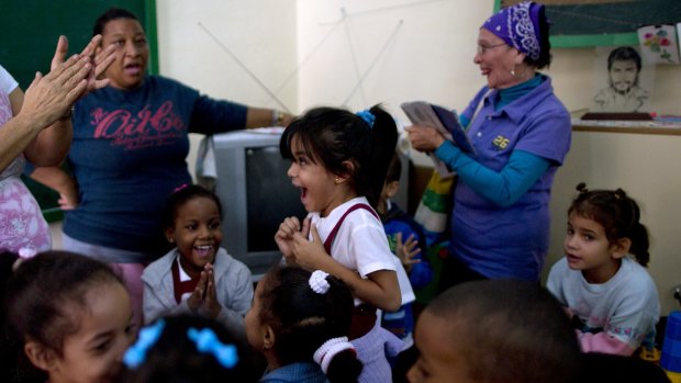 Students and teachers celebrate after listening to a live, nationally broadcast speech by Cuba's President Raul Castro about the country's restoration of relations with the United States, at a school in Havana, Cuba.