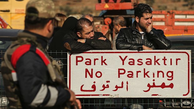 Syrians wait for other family members to cross into Turkey at the Cilvegozu border gate with Syria, near Hatay on Monday.