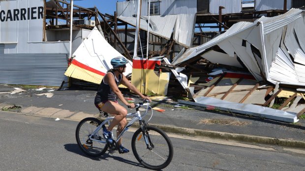 A resident cycling past a cyclone damaged business in the northern Queensland town of Rockhampton after Cyclone Marcia hit.