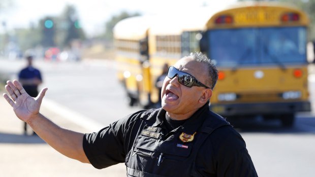 A police officer tries to give instructions to parents waiting to reunite with their children in Glendale, Arizona after two teenage students were shot on Friday at Independence High School in the Phoenix suburb. 