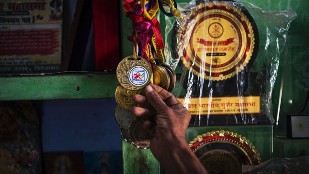 Dharam Pal Singh, a herder who regularly runs and claims to be 119 years old, with some of his running medals at home in Gudha, India.