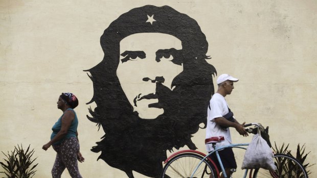 Lost in time: People walk in front of a mural of revolutionary leader Che Guevara in San Jose de las Lajas.