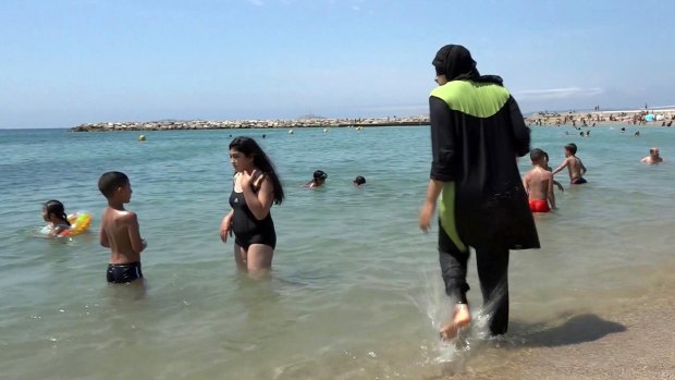 Nissrine Samali, 20, gets into the sea fully clothed in Marseille, southern France. The Cote d'Azur city of Cannes has banned burkinis.