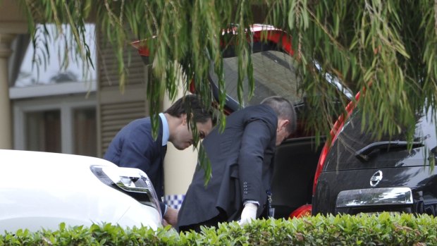Police examine the boot of a car outside the home of Phil Walsh on Friday.