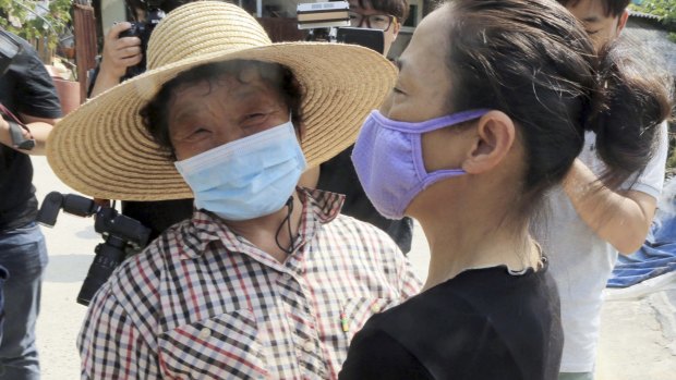 Women wearing masks as a precaution against the MERS virus celebrate after their village reopened following two weeks of isolation for quarantine in South Korea.
