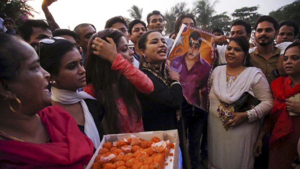 Fans hold a poster of Bollywood star Salman Khan and distribute sweets as they gather outside his residence to celebrate the news of his acquittal in Mumbai, India on Thursday.