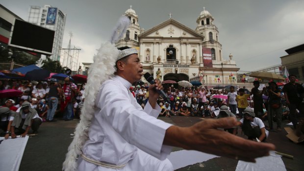 A protester dressed as a priest performs during a Christmas-theme street play to protest alleged extra-judicial killings in Manila.