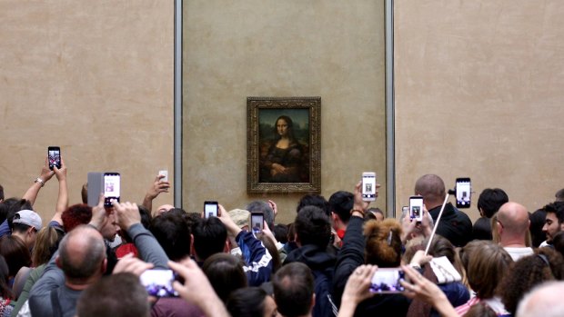 Tourists crowd the Mona Lisa at the Louvre, Paris.