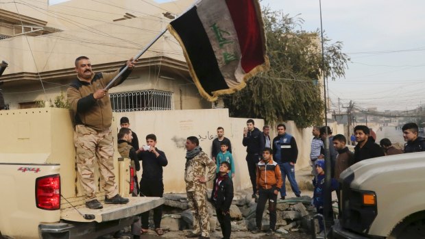 An Iraqi soldier waves the national flag as security forces patrol on the eastern side of Mosul, Iraq, on January 18. 