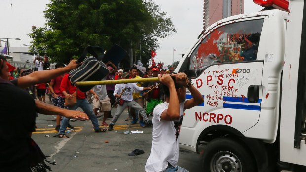 Protesters hit a Philippine National Police van after it rammed into protesters outside the US embassy in Manila on Wednesday.