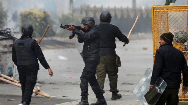 A Pakistani police officer aims his gun towards the protesters during a clash in Islamabad.