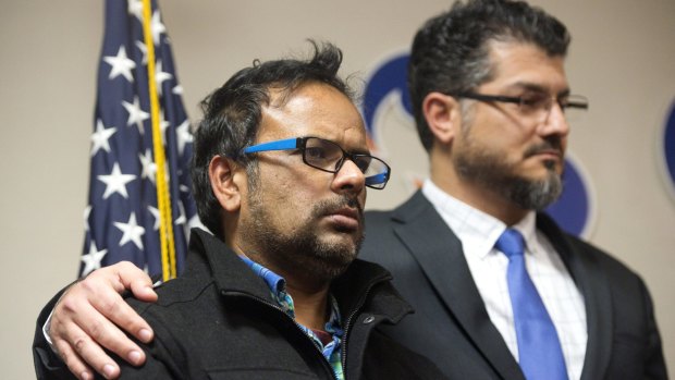 Farhan Khan, left, brother-in-law of one of the suspects involved in a shooting in San Bernardino, California, is held by Hussam Ayloush, executive director of the Council on American-Islamic Relations, during a news conference on Wednesday.