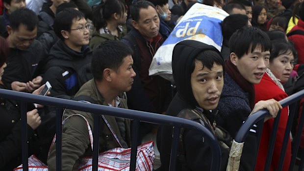 Stranded passengers wait at the barricades set up by policemen in a square outside Guangzhou Railway Station.