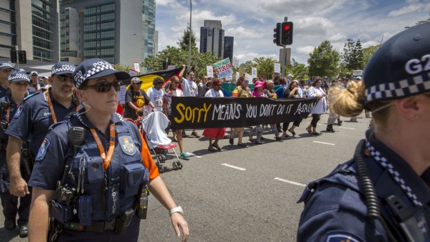 Police officers flank the protesters marching through the CBD.