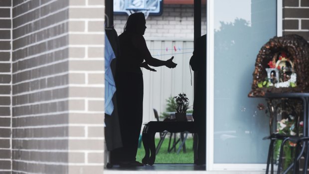 A woman argues with police as her home is raided in Fairfield Heights.