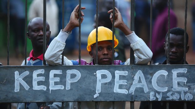 Kenyans lock themselves behind a gate with a Keep Peace sign as others burn tyres to protest.