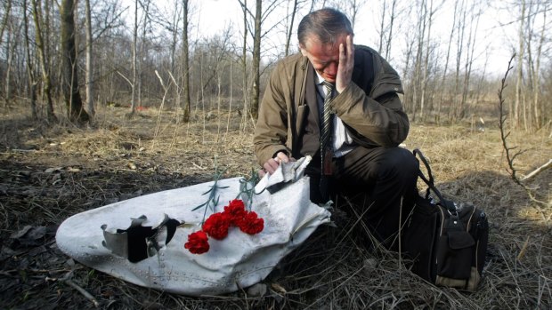 Polish Ian Grushinski grieves by a piece of the wreckage at a plane crash site near Smolensk on Sunday, April 11, 2010.