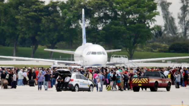 People stand on the tarmac at Fort Lauderdale-Hollywood International Airport after a shooter opened fire inside the terminal.