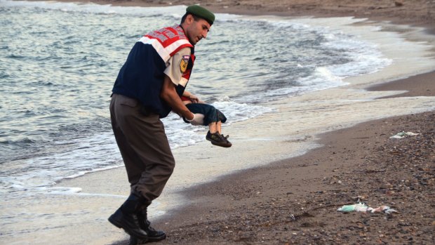 A Turkish police officer carries three-year-old Aylan Kurdi after he drowned.