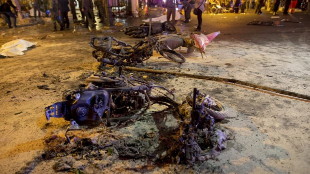 Wreckage of motorcycles are seen as security forces and emergency workers gather at the scene of a blast in central Bangkok on Monday.