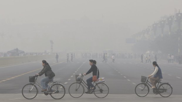 Chinese women cycle through smog and pollution over Beijing's Tiananmen Square. 