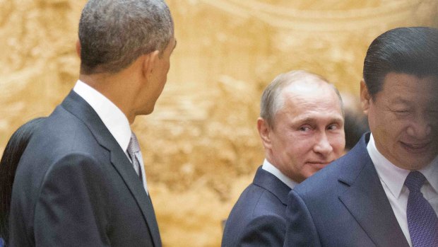 Vladimir Putin looks back at Barack Obama as they arrive with Chinese President Xi Jinping at an APEC session in Beijing on Tuesday.