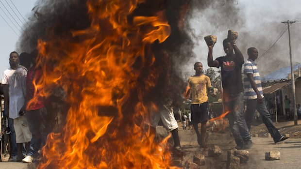 A crowd lights a fire and uses large  cobblestones to make a roadblock in the suburb of Nyakabiga on election day, July 21, 2015. 