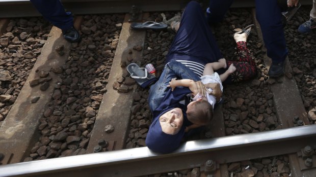 A woman lies on the track with a baby as she is detained in the Hungarian town of Bicske.