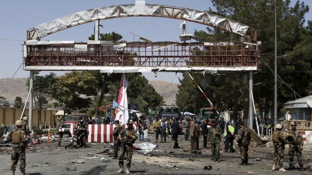 Members of the Afghan security forces stand at the site of a car bomb blast at the entrance gate to the Kabul airport on Monday.
