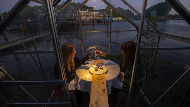 Volunteers at the Mediamatic restaurant seated in small glasshouses toast during a try-out.