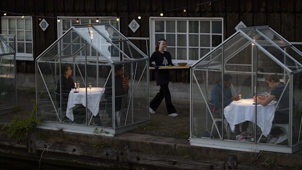 Staff at the Mediamatic restaurant serve food to volunteers seated in small glasshouses during a try-out of a setup which respects social distancing.