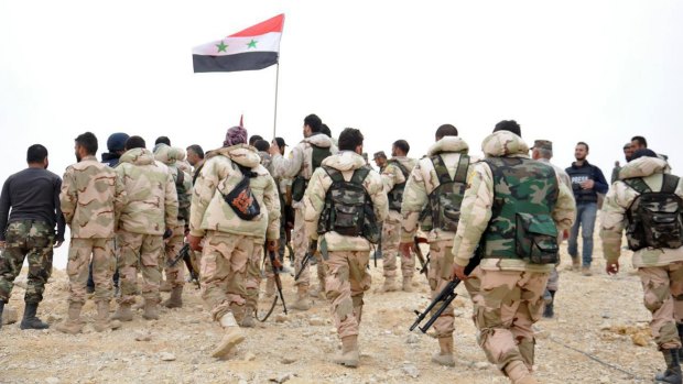 Syrian soldiers gather around a Syrian flag in Palmyra on Sunday.