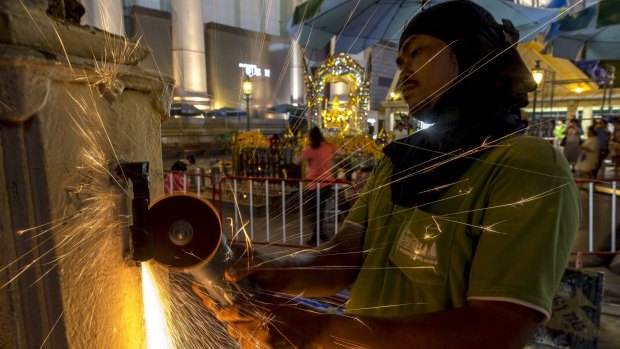 A worker fixes a fence at the Erawan Shrine after Monday's deadly blast.