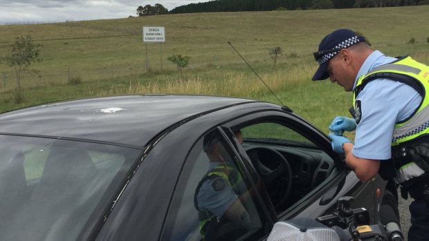An ACT Policing officer performs a drug test on the side of the Kings Highway near Queanbeyan.