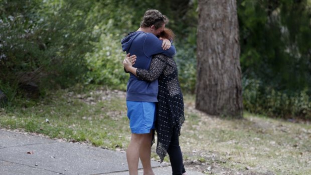 Two people comfort each other outside the Eltham North home.
