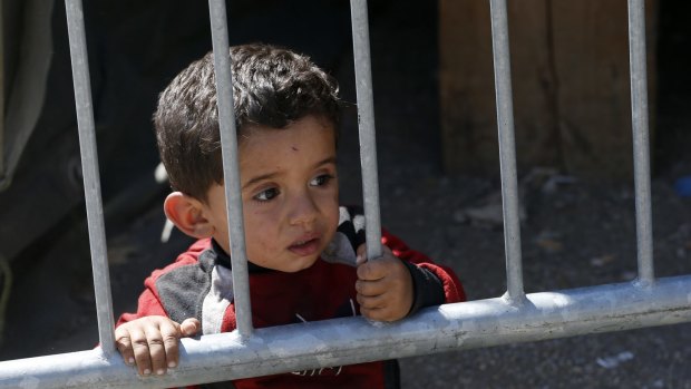 A child looks through the fence next to a migrant processing centre in the southern Serbian town of Presevo on Monday.