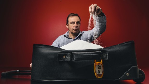 Heart Foundation CEO Tony Stubbs with a suitcase containing 23 kilograms of sugar - the quantity of sugar you would consume if you drank a 600ml bottle of Coke every day for a year. 