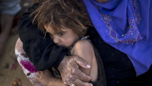 Elderly Syrian refugee Halima Ali holds her granddaughter Amal, 4, while sitting outside their tent at an informal settlement near the Syrian border.