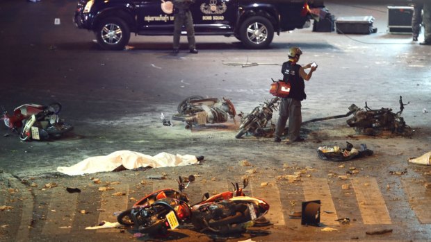 Carnage ... A policeman photographs debris from an explosion in central Bangkok, Thailand. 